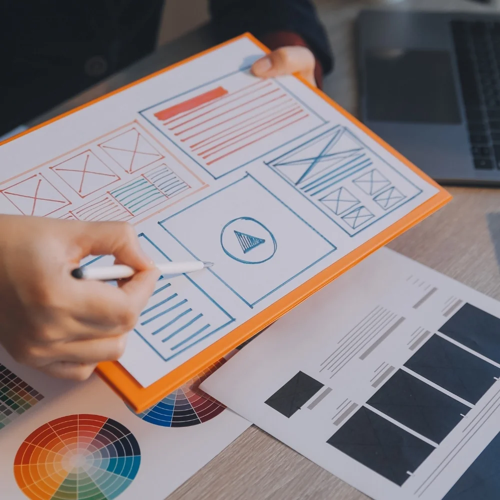 Designer sketching website wireframes on paper with pen and ruler